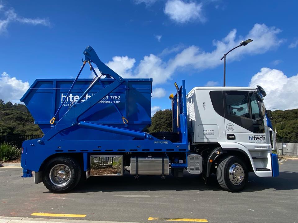 photo of a hitech disposals truck carrying a blue skip waste bin