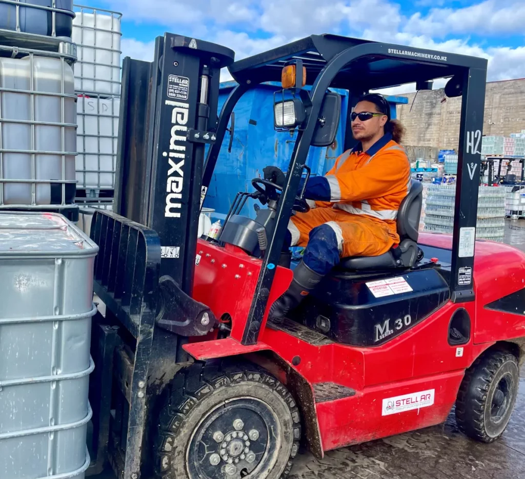 man driving red forklift on a waste processing site